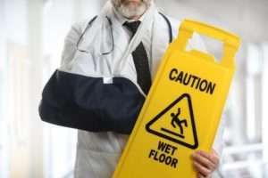 Injured doctor holding wet floor sign