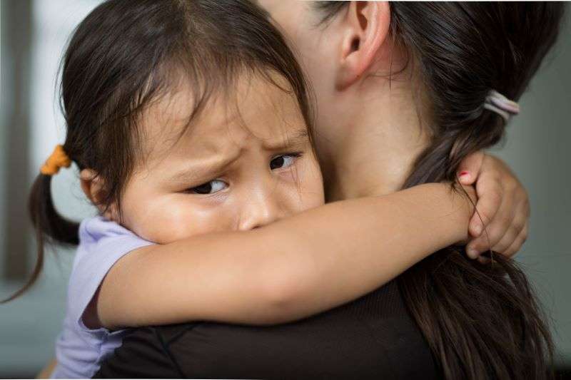 scared little girl holding her mother